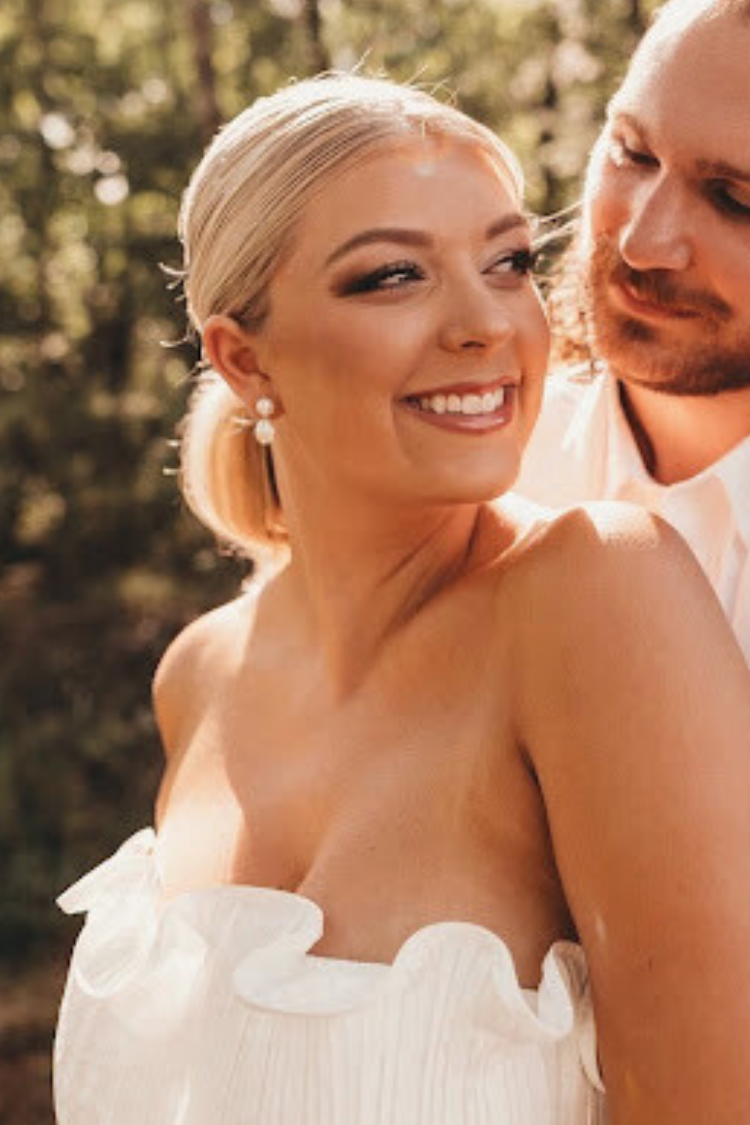 Bride with flawless wedding day makeup and styled hair by AD Artistry, beaming with joy