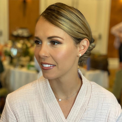 Bride with elegant updo and natural wedding makeup, wearing a soft robe before her ceremony.
