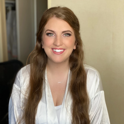 Bride with long red hair and classic bridal makeup featuring smokey eyes and pink lips, wearing white silk robe during morning preparations