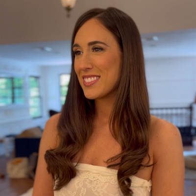 Bride with sleek dark brown hair styled in elegant waves, wearing lace dress and natural bridal makeup with radiant smile