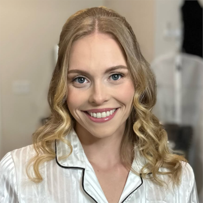 Bride in striped silk pajamas with romantic curled blonde hair and natural bridal makeup during wedding morning preparations