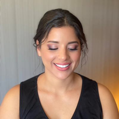 Bridesmaid with romantic low bun and soft purple eyeshadow, featuring wispy face-framing pieces and glowing bridal party makeup